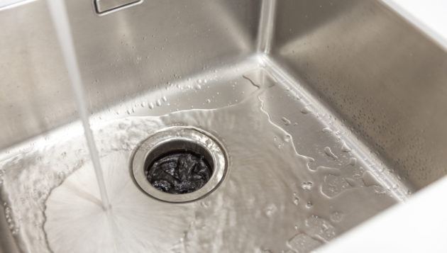 water running into the garbage disposal of a kitchen sink