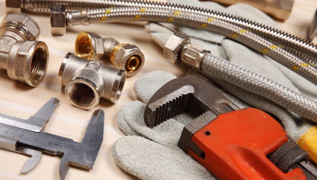 plumbing tools and system parts laid down on a wooden surface