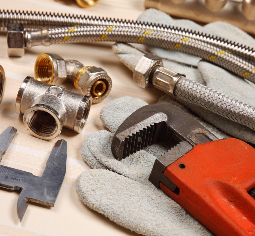 plumbing tools and system parts laid down on a wooden surface