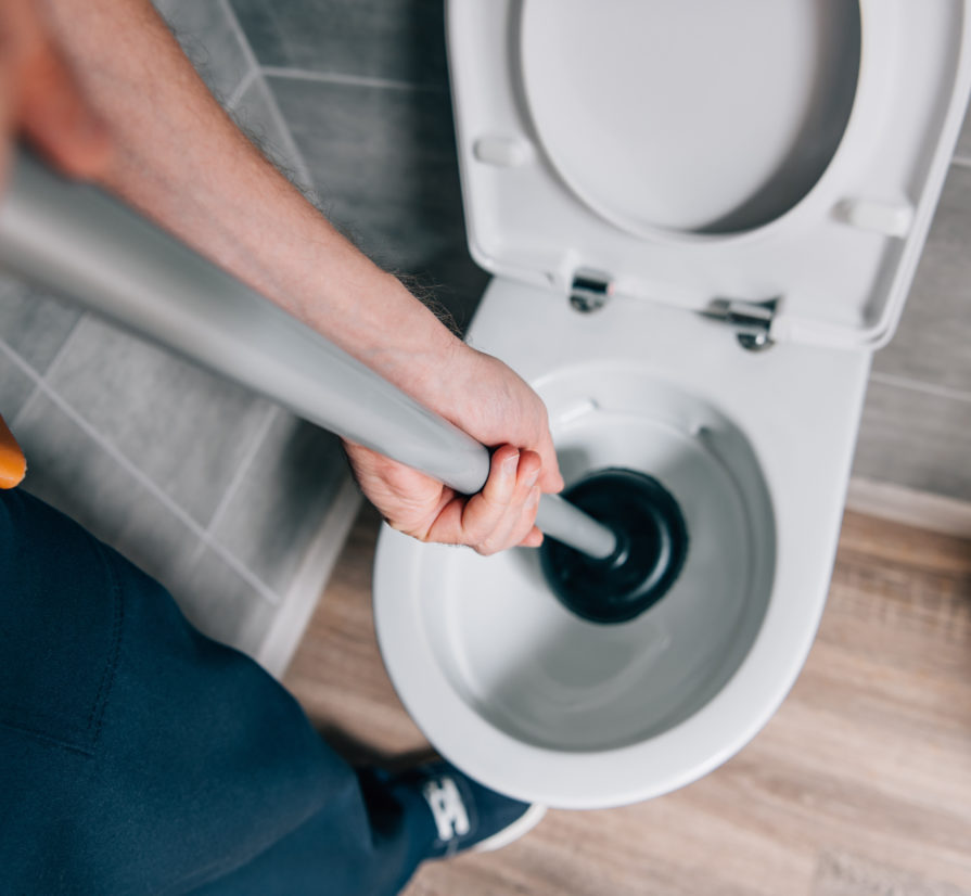 a plumber using a plunger on a toilet
