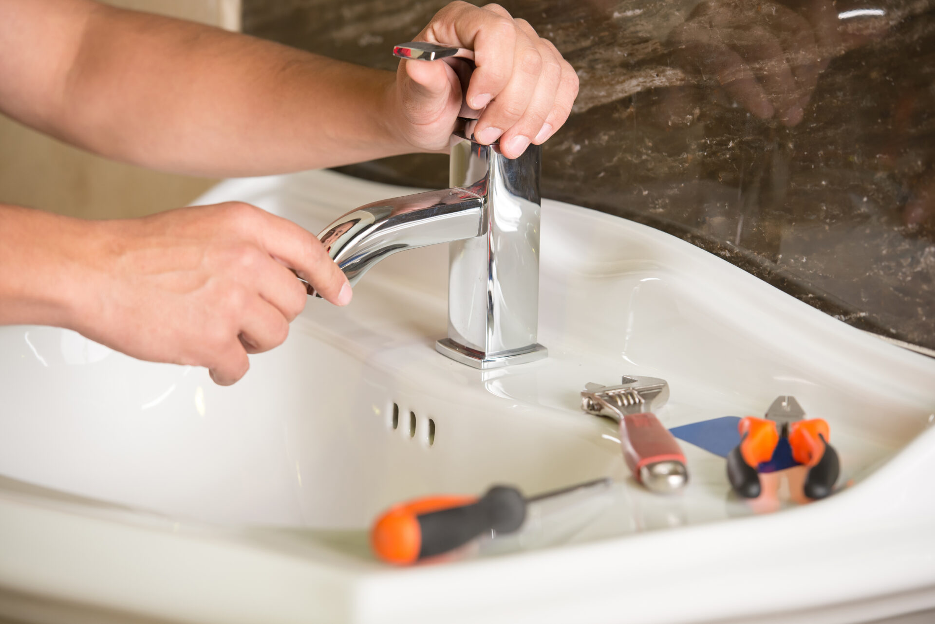 plumber adjusting the faucet and handle of a bathroom sink