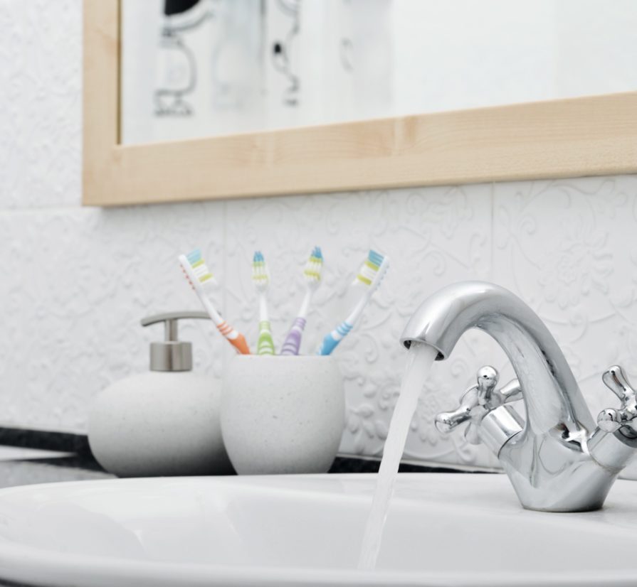 a bathroom in Spring Branch with a cup of toothbrushes next to a running sink