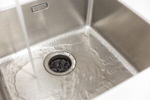 water from a faucet draining into a San Antonio garbage disposal