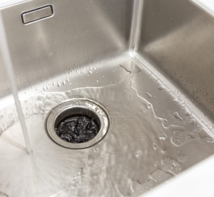 water from a faucet draining into a San Antonio garbage disposal