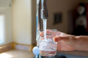 a woman's hand filling up a glass of water from a kitchen sink