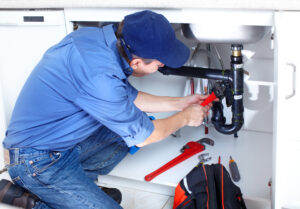 experienced plumber working under a sink fixing a p-trap