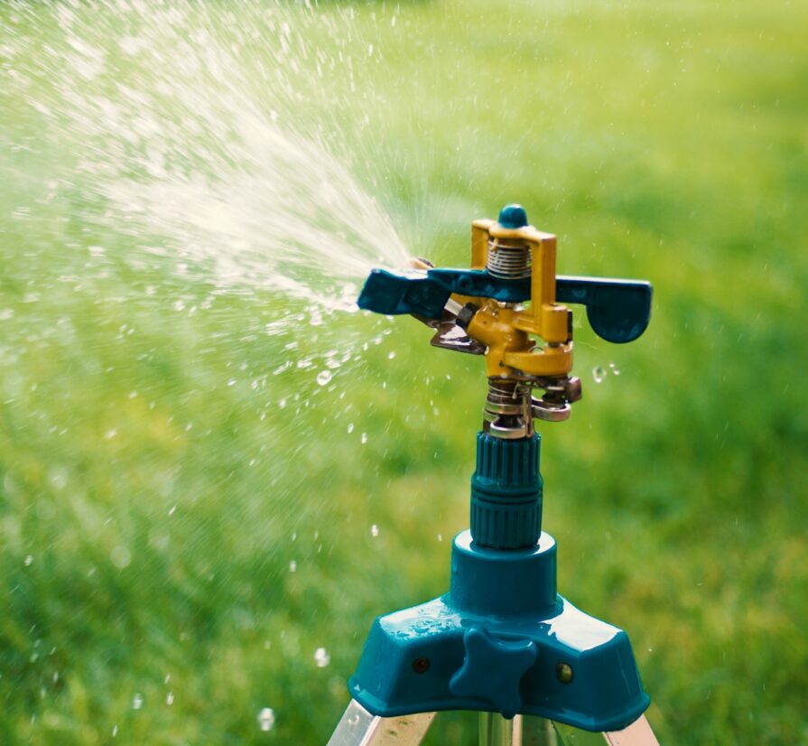 closeup of a sprinkler system spraying water on green grass